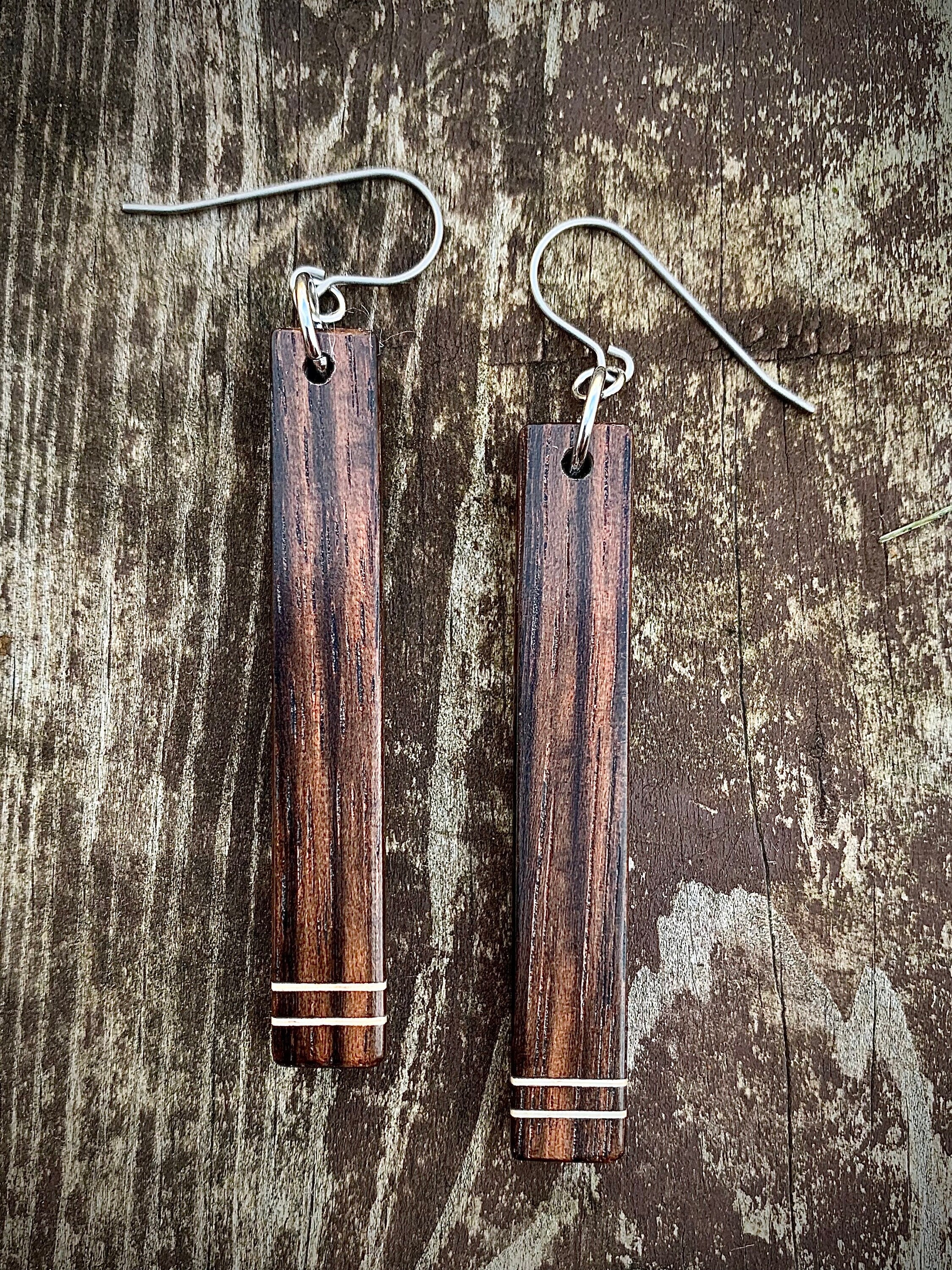 Two dark wood dangle earrings with two horizontal white stripes.