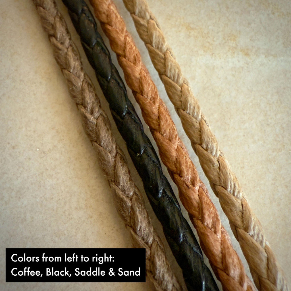 Four stripes of coffee, black, saddle and sand braided cotton rope on a textured beige surface.